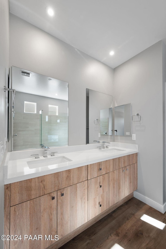 bathroom with hardwood / wood-style floors, vanity, and tiled shower