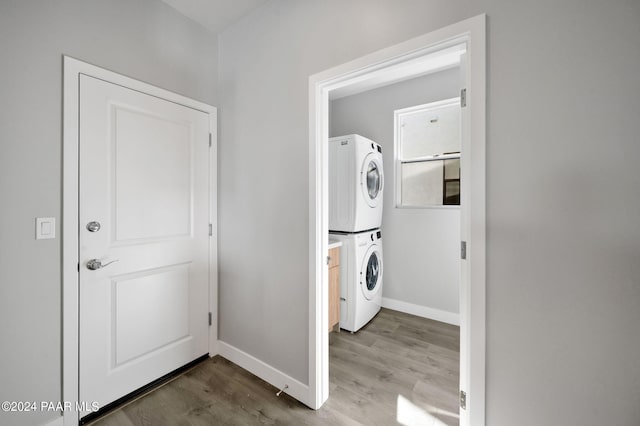 laundry area with hardwood / wood-style flooring and stacked washer / drying machine