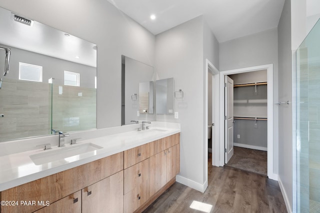 bathroom with hardwood / wood-style floors, vanity, and a tile shower