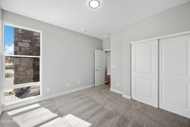 unfurnished bedroom featuring multiple windows, a closet, and light colored carpet