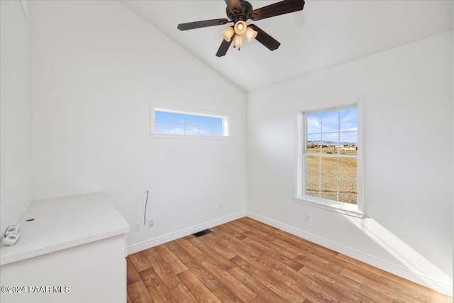 empty room with vaulted ceiling, a healthy amount of sunlight, ceiling fan, and light hardwood / wood-style flooring