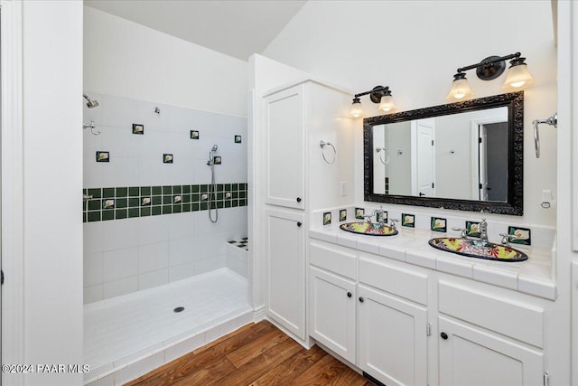 bathroom featuring tiled shower, wood-type flooring, and vanity