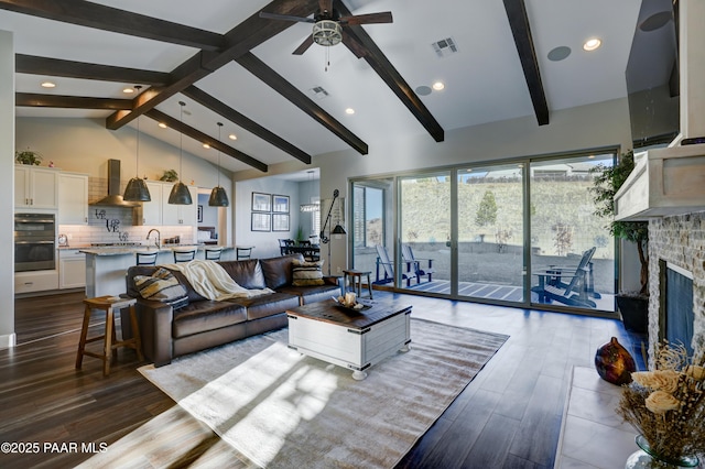 living room with high vaulted ceiling, a tile fireplace, sink, ceiling fan, and beamed ceiling