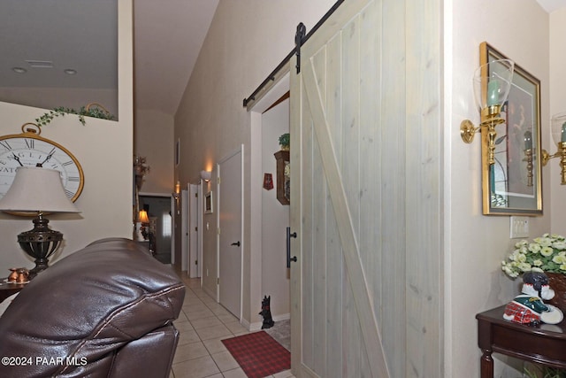 hall featuring light tile patterned floors, a barn door, and vaulted ceiling