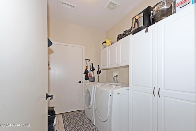 clothes washing area featuring cabinets, light tile patterned floors, and washer and dryer