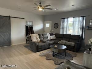 living room with a barn door, light hardwood / wood-style flooring, and ceiling fan