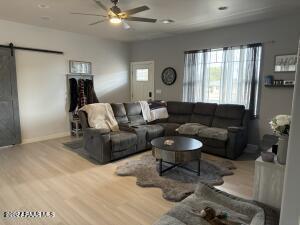 living room with a barn door, ceiling fan, and wood-type flooring