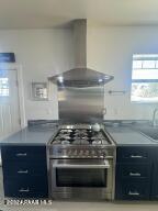 kitchen with sink, stainless steel range with gas cooktop, and wall chimney range hood