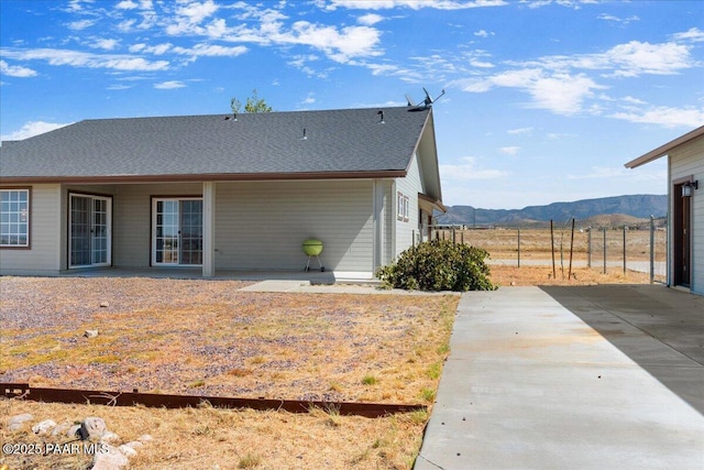 back of house with concrete driveway, fence, and a mountain view