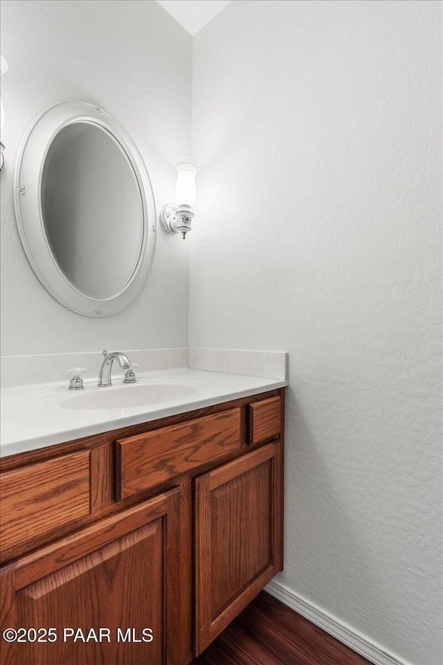 bathroom with baseboards, wood finished floors, and vanity