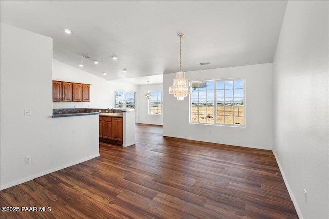 kitchen with dark wood-type flooring, vaulted ceiling, a healthy amount of sunlight, and a notable chandelier