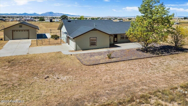 ranch-style house with concrete driveway, fence, a detached garage, and a mountain view