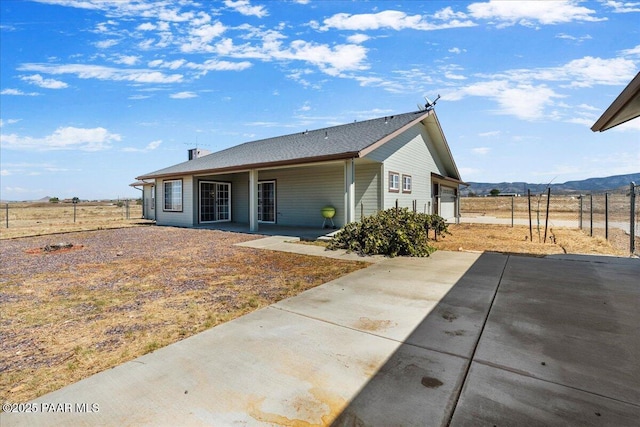 back of property with fence, a patio, a mountain view, and concrete driveway