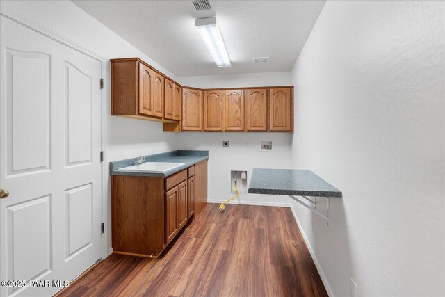 clothes washing area featuring dark wood-style floors, hookup for an electric dryer, a sink, hookup for a washing machine, and cabinet space