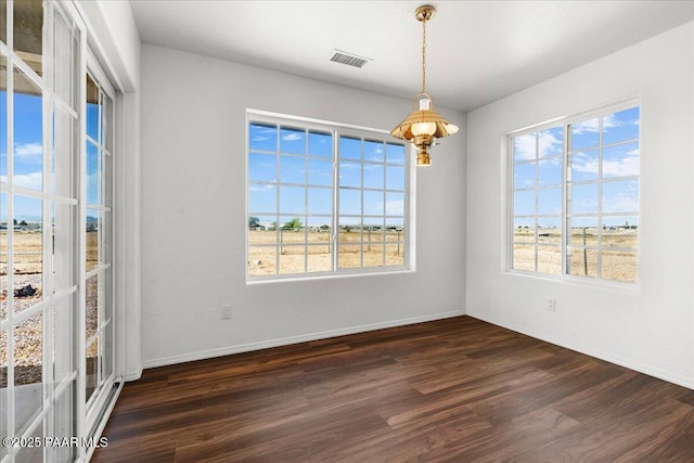 empty room featuring visible vents, a healthy amount of sunlight, and dark wood finished floors