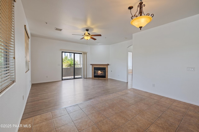 1735 Oro Dr, Cottonwood, AZ 86326 - unfurnished living room with a ceiling fan, arched walkways, tile patterned flooring, a tiled fireplace, and baseboards