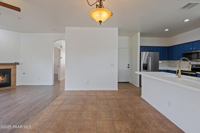 1735 Oro Dr, Cottonwood, AZ 86326 - kitchen featuring blue cabinetry, appliances with stainless steel finishes, arched walkways, light countertops, and open floor plan