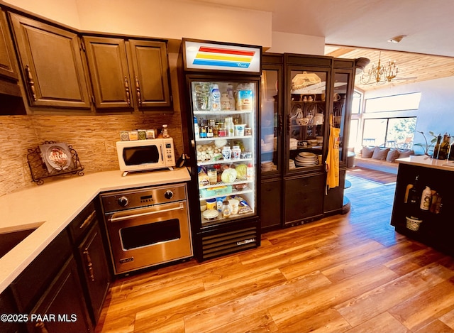 28555 N Feather Mountain Rd, Paulden, AZ 86334 - kitchen with oven, white microwave, light countertops, light wood finished floors, and backsplash