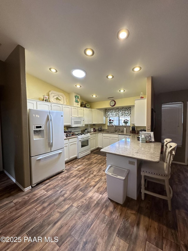 6217 N Little Papoose Dr, Prescott Valley, AZ 86314 - kitchen with a peninsula, white appliances, dark wood-style floors, white cabinets, and a breakfast bar area