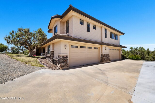 13175 N Bull Run Rd, Prescott, AZ 86305 - view of front of house with an attached garage, stone siding, and concrete driveway