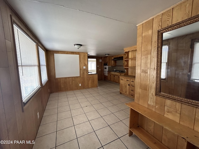 interior space with light tile patterned floors, wooden walls, and stainless steel oven