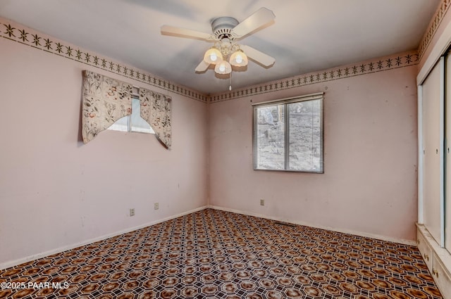 spare room with a ceiling fan, a wealth of natural light, and baseboards