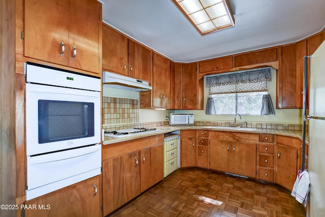 kitchen with white appliances, light countertops, a warming drawer, and a sink