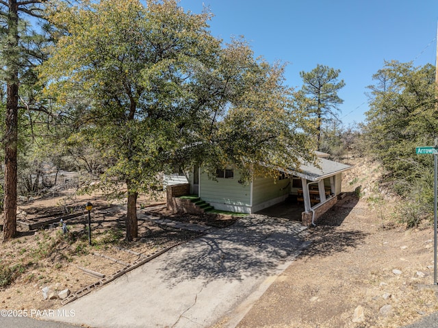 view of front of house with dirt driveway and an attached carport
