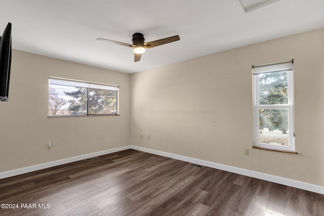 empty room with dark wood-type flooring, ceiling fan, and a wealth of natural light