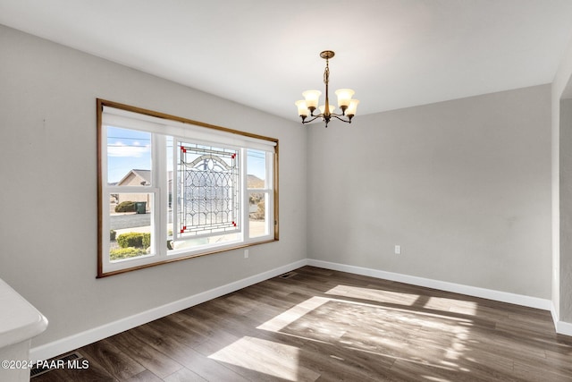 unfurnished dining area featuring dark hardwood / wood-style floors and an inviting chandelier