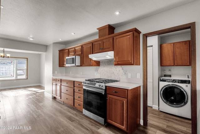 kitchen with tasteful backsplash, appliances with stainless steel finishes, washer / dryer, and wood-type flooring