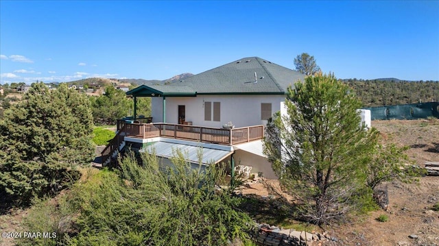 rear view of property with a deck with mountain view and stucco siding