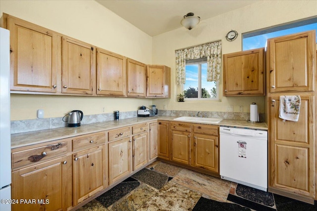 kitchen with light brown cabinetry, white dishwasher, a sink, and light countertops