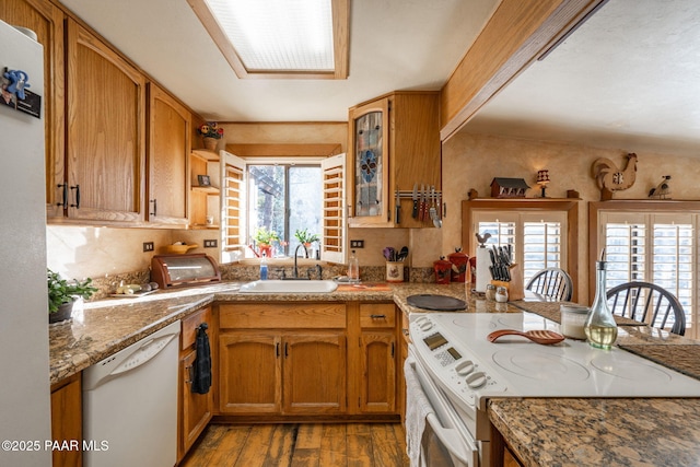 kitchen with backsplash, sink, white appliances, light hardwood / wood-style flooring, and light stone counters