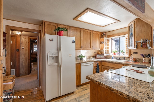 kitchen featuring light hardwood / wood-style floors, sink, white appliances, and dark stone countertops