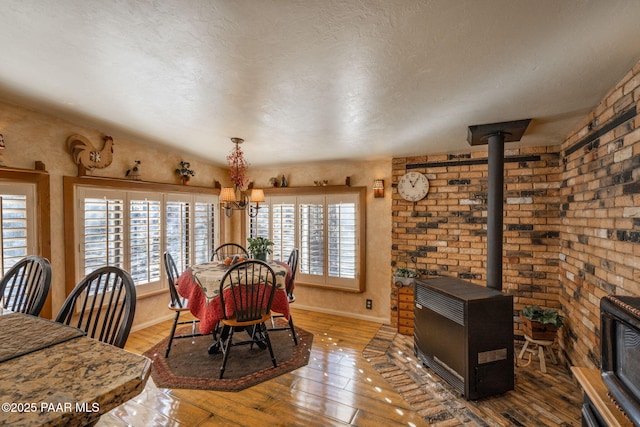 dining space featuring hardwood / wood-style flooring, a wood stove, a textured ceiling, and a notable chandelier