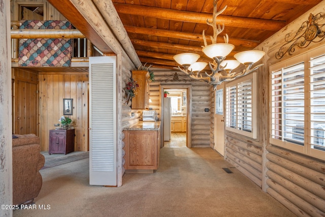 interior space featuring wooden ceiling, light colored carpet, rustic walls, a chandelier, and beamed ceiling