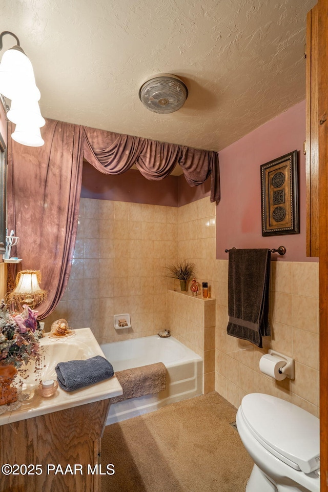 bathroom featuring toilet, tile walls, a washtub, and a textured ceiling