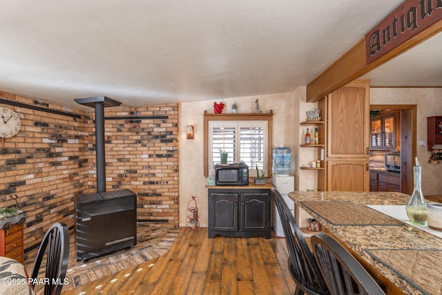 kitchen featuring a wood stove, brick wall, and dark hardwood / wood-style floors