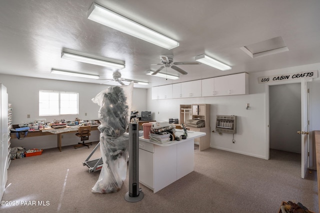 kitchen featuring ceiling fan, white cabinetry, heating unit, and light carpet