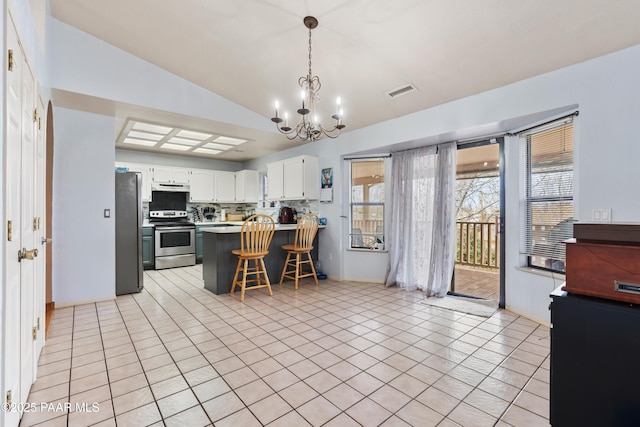 kitchen with lofted ceiling, under cabinet range hood, a peninsula, visible vents, and appliances with stainless steel finishes