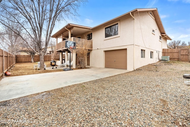 view of front facade with concrete driveway, a fenced backyard, an attached garage, and stucco siding