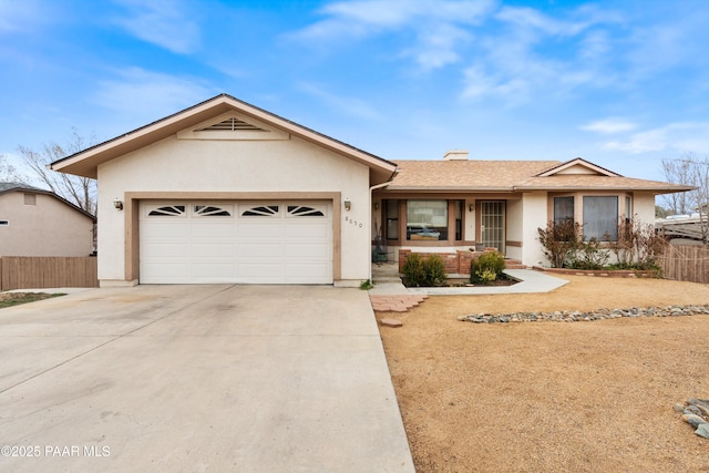 ranch-style home with driveway, an attached garage, fence, and stucco siding