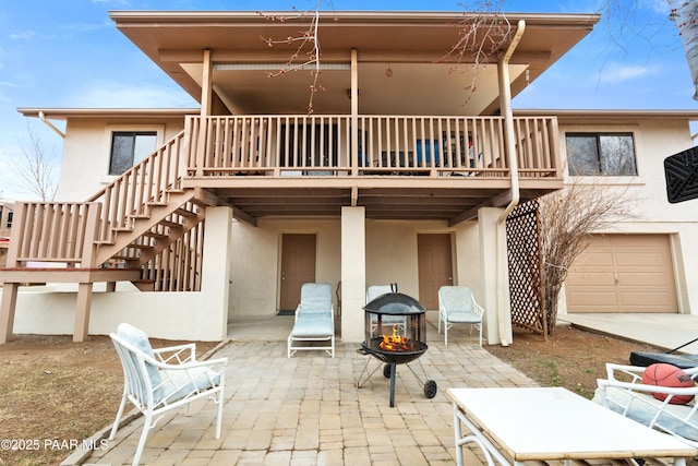 back of property featuring stairs, an outdoor fire pit, a patio area, and stucco siding