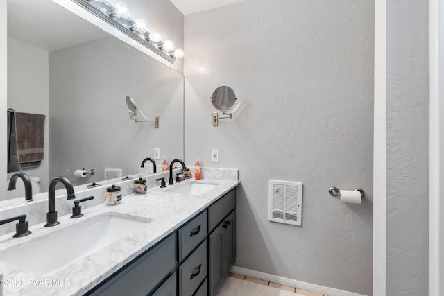 bathroom featuring double vanity, visible vents, a sink, and a textured wall