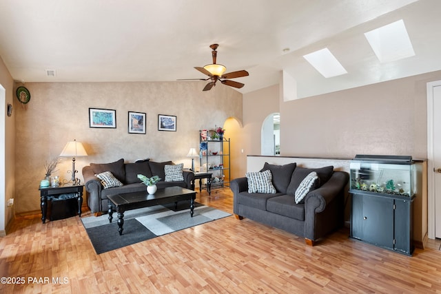 living room with lofted ceiling, arched walkways, visible vents, a ceiling fan, and light wood-type flooring