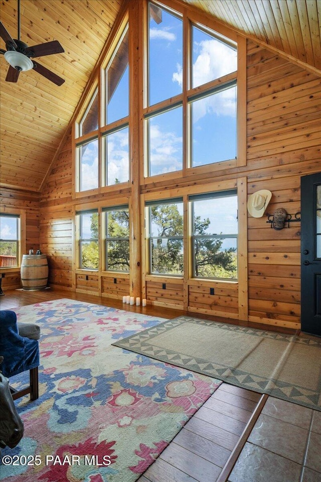 interior space with high vaulted ceiling, wood walls, ceiling fan, and wood ceiling