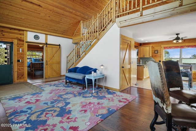 entrance foyer with wooden ceiling, ceiling fan, light wood-type flooring, wood walls, and a barn door