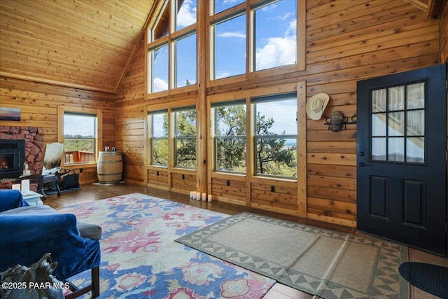 living room featuring high vaulted ceiling, wooden ceiling, hardwood / wood-style floors, and a stone fireplace