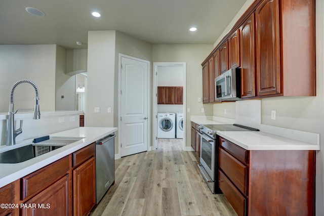 kitchen featuring light wood-type flooring, washing machine and dryer, stainless steel appliances, and sink